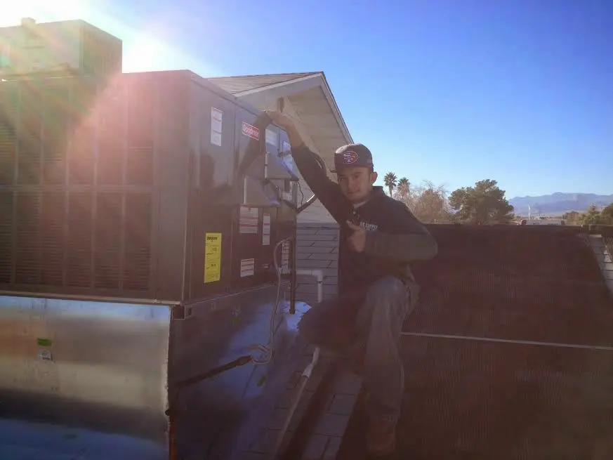 HVAC technician performing AC Tune-Up on a rooftop unit in Brownsville